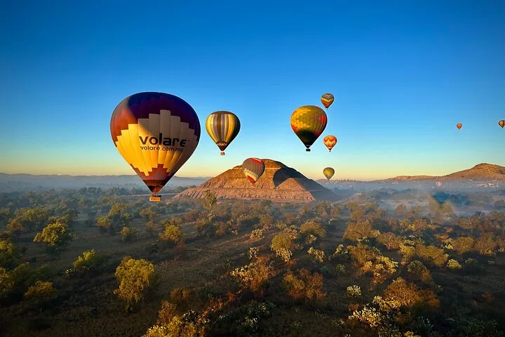 A balloon with the Volare name drifting past the Pyramid of the Sun at sunrise