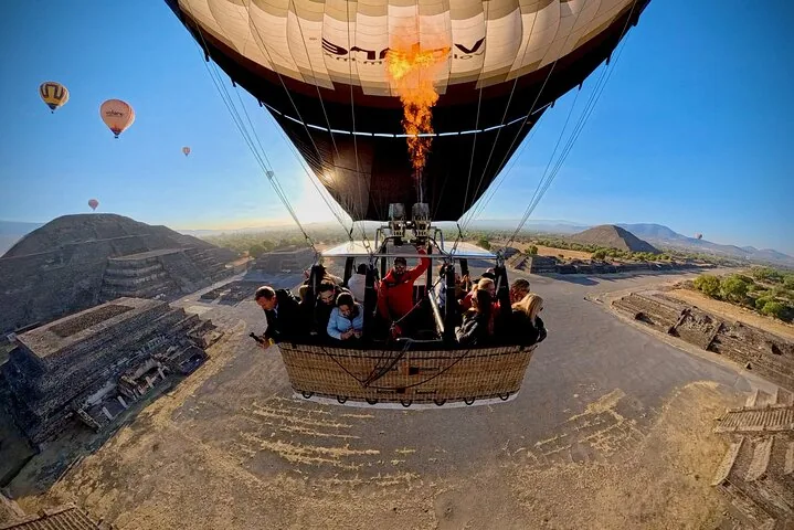 A balloon and its basket crossing the Avenue of the Dead with burner flame lit