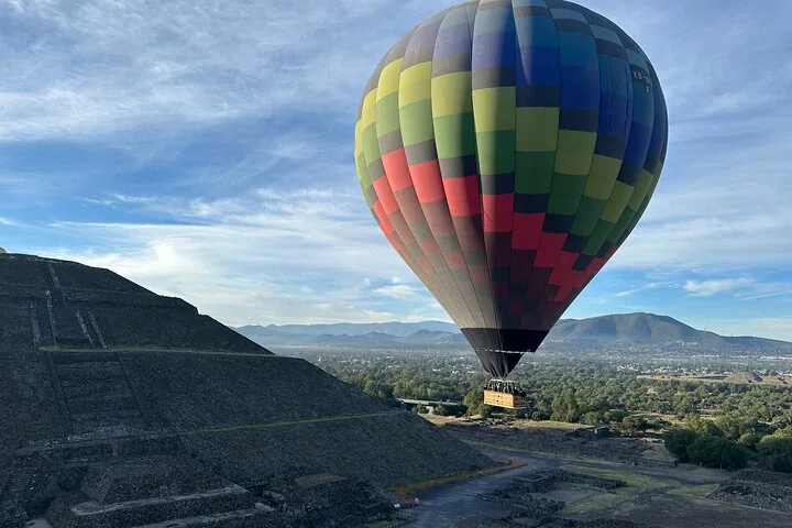 A multicolored balloon rising beside the stepped side of the Pyramid of the Sun
