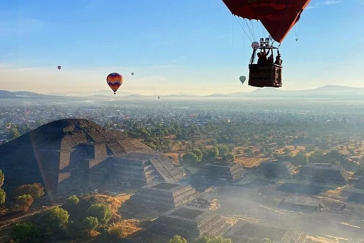 A balloon basket in the air above the Pyramid of the Moon and the valley