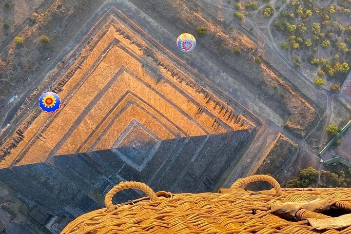 Top-down view of stepped pyramid terraces with two balloons and a basket rim in frame