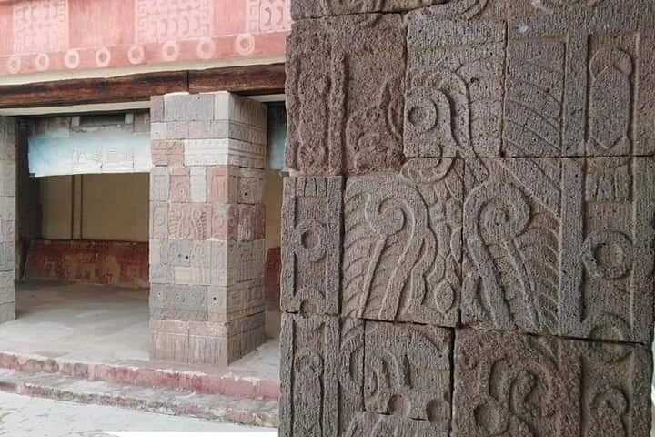 Carved stone reliefs and painted red murals at a Teotihuacán site building