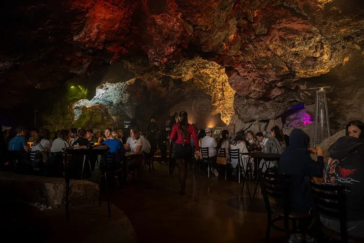 Wide view of a large cave dining hall with tables and warm lighting