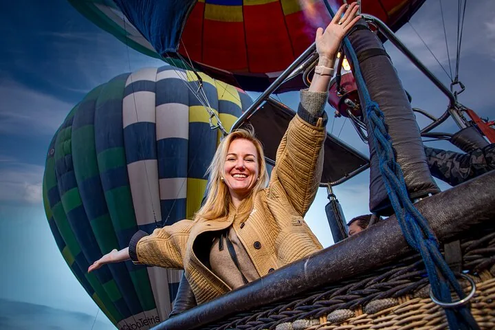 A woman leaning out of a wicker basket with a striped balloon behind her