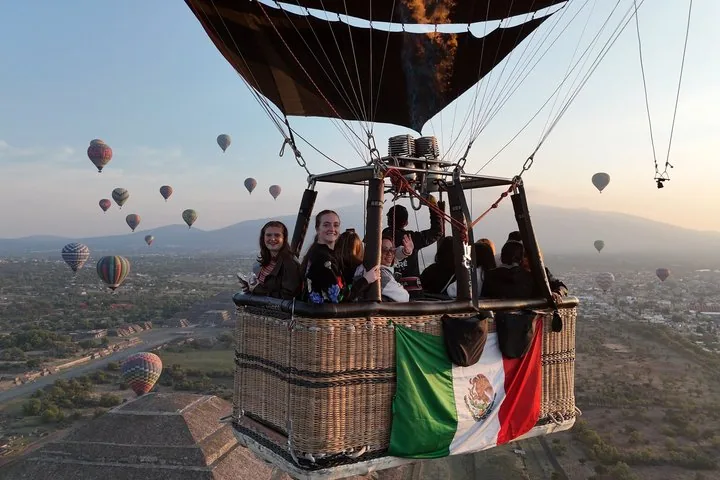 A full basket carrying a Mexican flag drifting over the Pyramid of the Sun